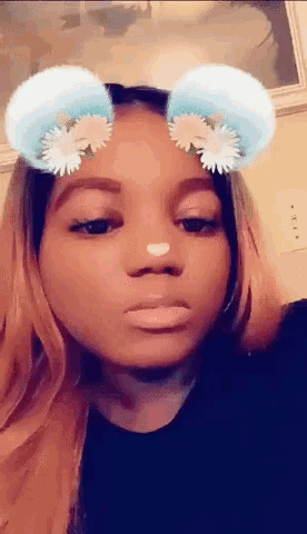 a woman wearing a snapchat filter with flowers on her ears