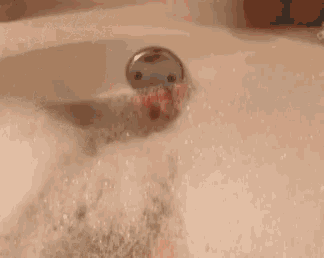 a close up of a person 's leg in a bathtub with bubbles coming out of it .