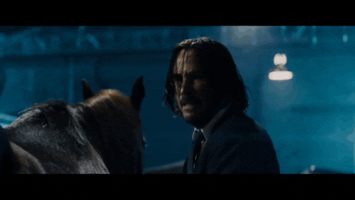 a man in a suit is standing next to a horse