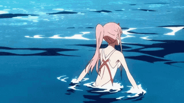 a girl with pink hair is standing in a body of water .