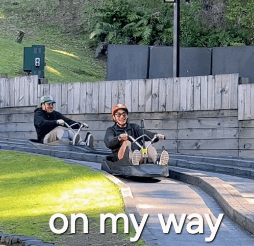 two men are sledding down a hill with the words " on my way " behind them