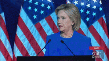 a woman stands at a podium in front of an american flag and says shift