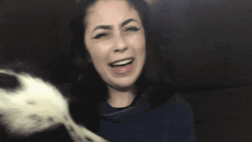 a black and white dog is sniffing a person 's face