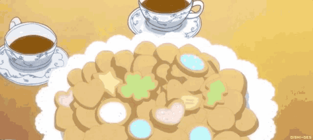 a plate of cookies sits on a table with two cups of tea