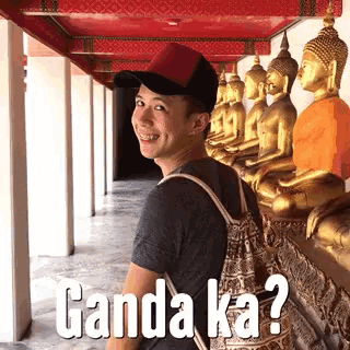 a man standing in front of a row of buddha statues with ganda ka written on the bottom