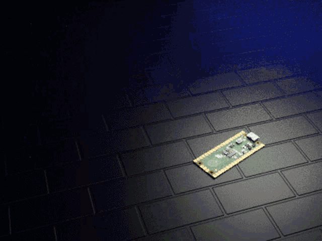 a green and gold motherboard is laying on a black tile floor