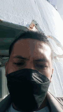 a man wearing a black face mask looks down