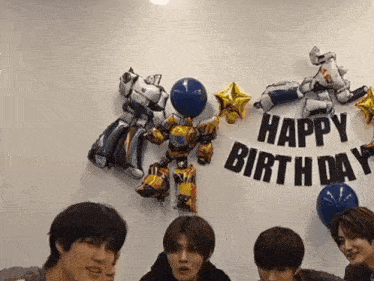 a group of young men are standing in front of a happy birthday sign