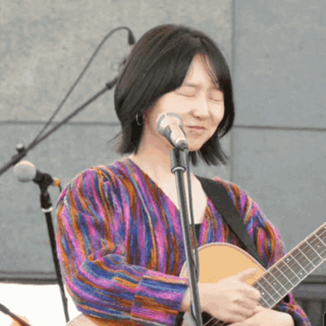 a woman singing into a microphone with her eyes closed
