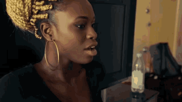 a woman wearing hoop earrings and braids looks at something