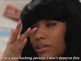 a woman with pink nails is making a face and saying i 'm a nice fucking person