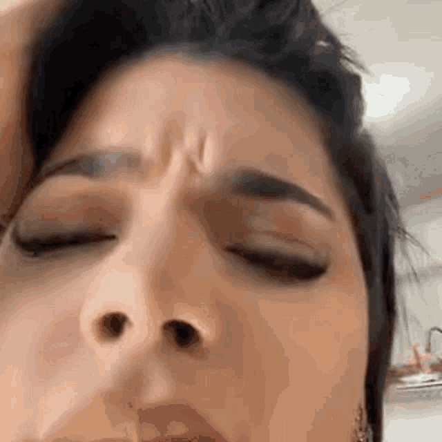 a close up of a woman 's face with her eyes closed and a slight wrinkle on her forehead .