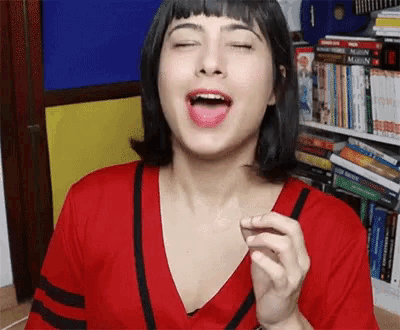 a woman in a red shirt is making a funny face with her tongue hanging out .