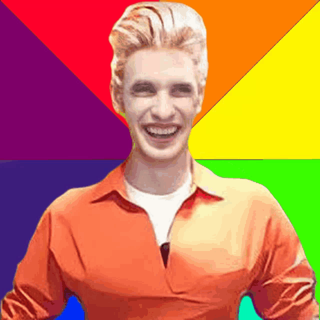 a man wearing an orange shirt is smiling in front of a rainbow background