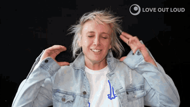 a woman wearing a denim jacket and a white shirt with the words love out loud in the corner