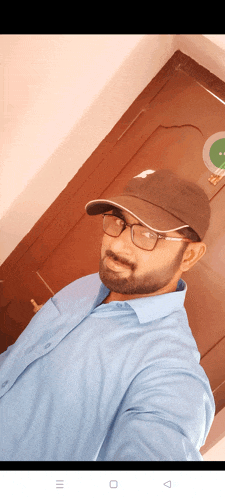 a man wearing a hat and glasses takes a selfie in front of a door that says ' exit ' on it