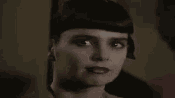 a close up of a woman 's face with a scarf around her head and red lipstick .