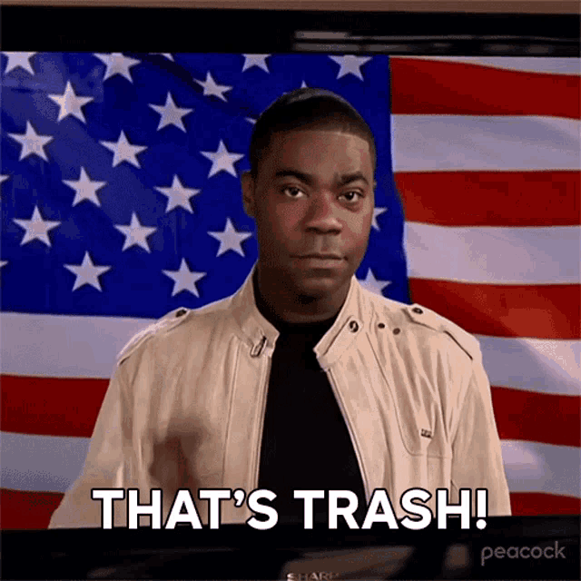 a man standing in front of an american flag with the words that 's trash
