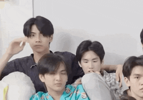 a group of young men sitting next to each other on a bed .