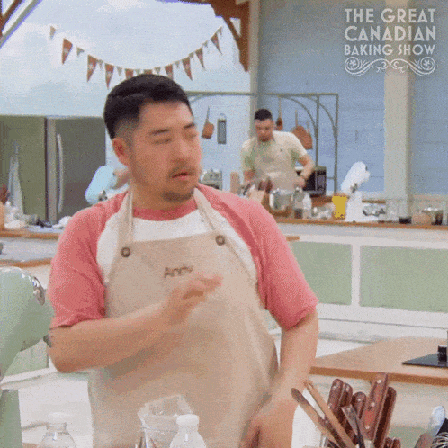 a man in an apron is standing in front of a sign that says the great canadian baking show