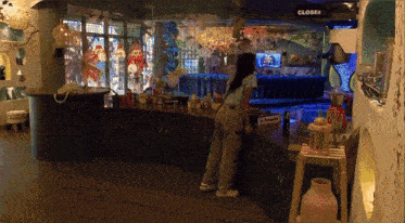 a woman stands at a counter in front of a sign that says closed