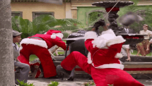 two men dressed as santa claus are playing with a fountain