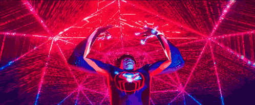 a man in a spiderman costume is standing in a room with a spider web in the background .