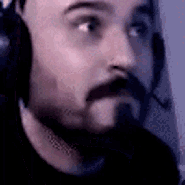a man with a beard and headphones on is looking at the camera .