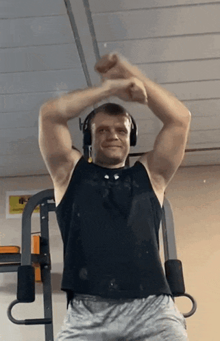 a man wearing headphones and a black tank top stands in front of a wall with a picture of a horse on it