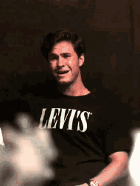 a man wearing a black levi 's shirt is making a funny face .