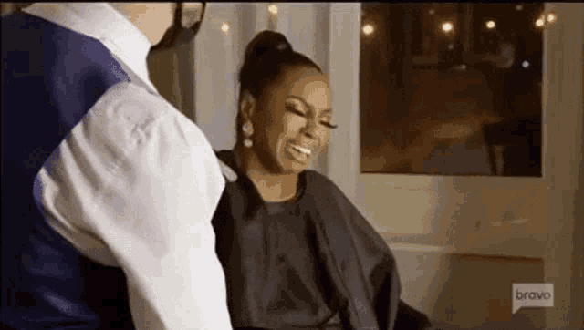 a woman is sitting in a chair getting her hair cut by a man in a suit .
