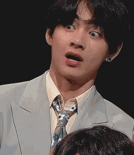 a man wearing a suit and tie is making a funny face