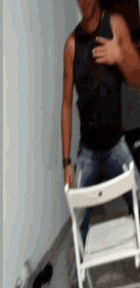 a man in a black tank top is sitting in a white chair