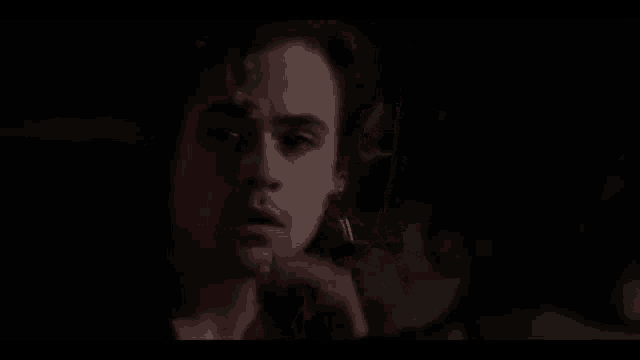 a close up of a man 's face in the dark with his hand on his face .