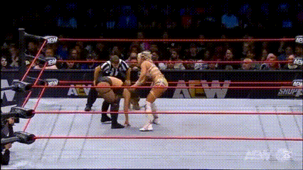 two women are wrestling in a ring with a referee watching