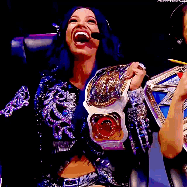 a woman with blue hair is holding a championship belt and smiling