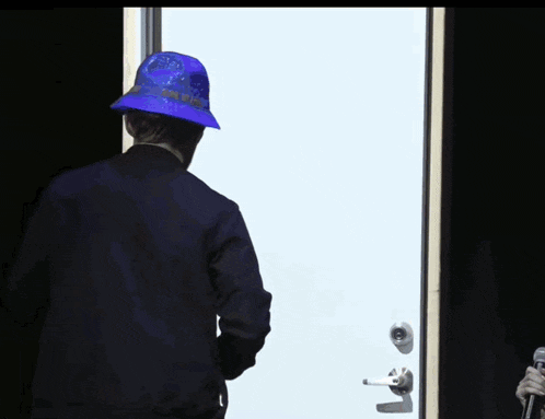 a man wearing a blue hat stands in front of a white door