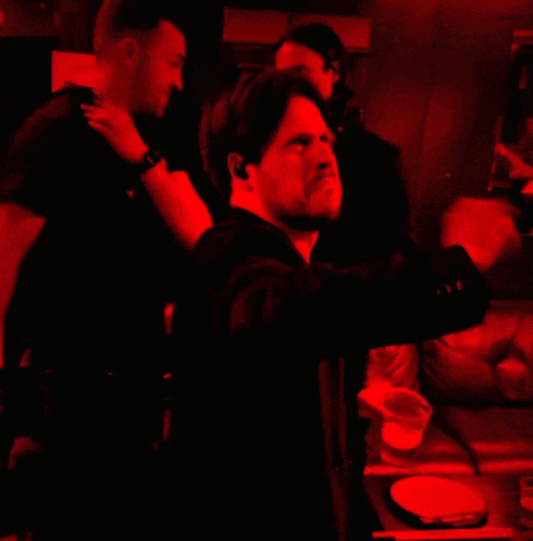 a man in a suit is standing in a red room