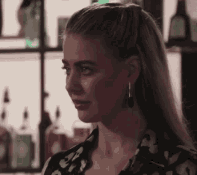 a woman wearing a leopard print shirt and earrings looks at the camera