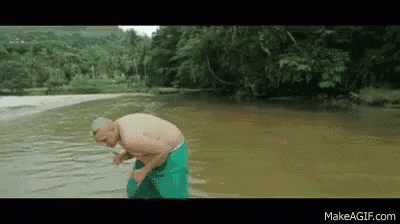 a shirtless man in green shorts is standing in the water