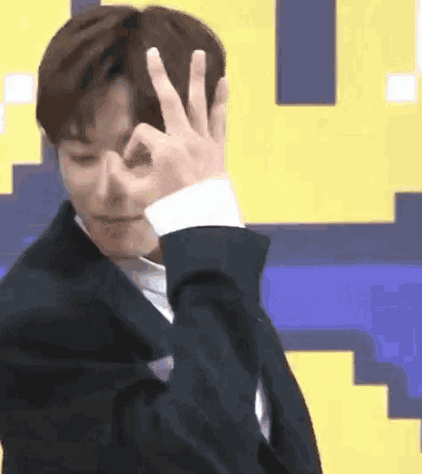 a young man in a suit is making a peace sign with his hands .