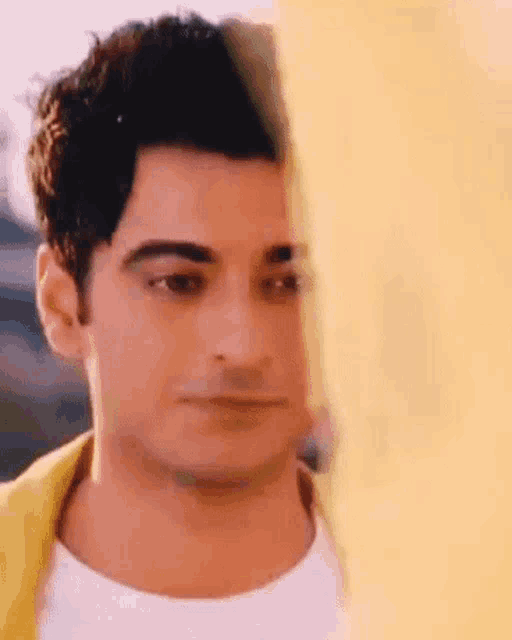 a close up of a man 's face behind a yellow wall .