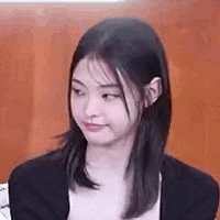 a close up of a woman making a funny face while sitting in front of a wooden wall .