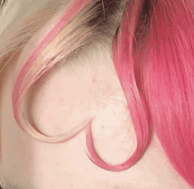 a close up of a woman 's hair with pink highlights