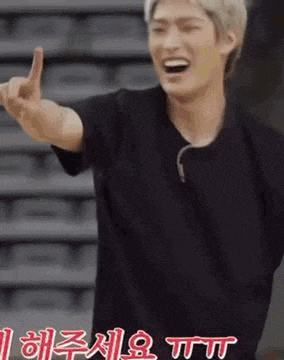 a man in a black shirt is giving the middle finger while smiling .