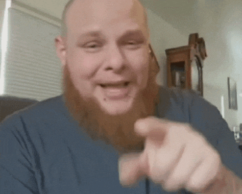a man with a beard and a tattoo on his wrist is blowing a kiss .