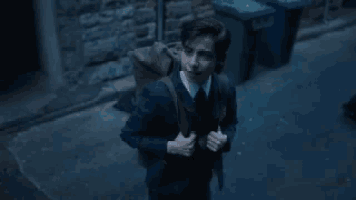 a man in a suit and tie is walking down a dark street