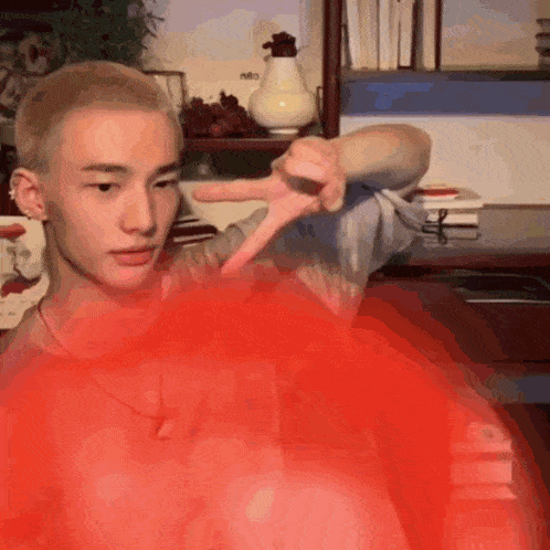 a man with a shaved head is making a peace sign with his hand .