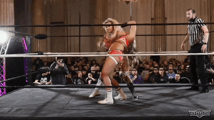two women are wrestling in a wrestling ring while a referee looks on .