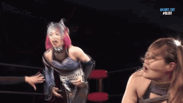 a woman with pink hair is standing in a wrestling ring with a mask on ..